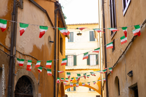Typical street with houses in Italy. Facade of a yellow building with Italian flags. Italian flag in an old town narrow street of a city in Italy