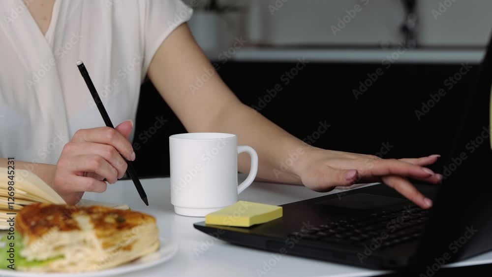 Young woman in kitchen during quarantine. Close up and cut view of girl working at home remote using laptop searching on the internet. Productive work. Young woman in kitchen during quarantine. Close up and cut view of girl working at home remote using laptop searching on the internet. Productive work.