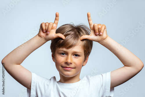 Foto Child making bull horn gesture on his head, portrait on white background
