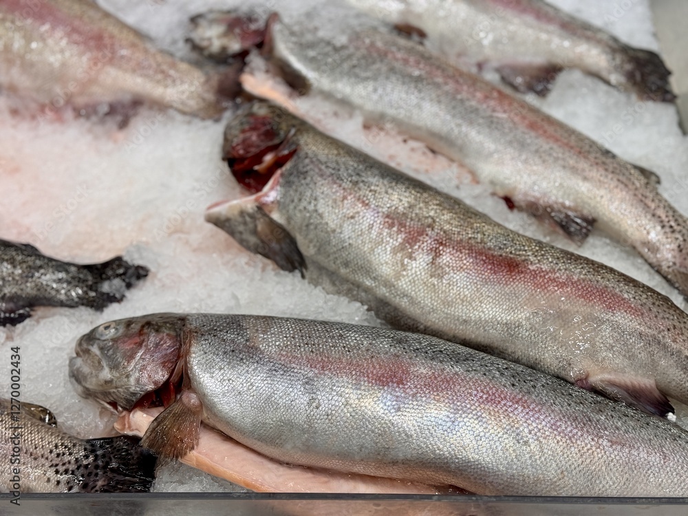 Raw steaks of rainbow trout chilled on shallow ice at the seafood market. An open shelf at the fish market Raw steaks of rainbow trout chilled on shallow ice at the seafood market. An open shelf at the fish market