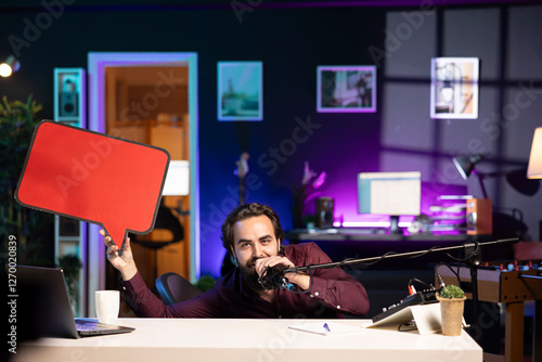 Man filming sponsored content, holding empty copy space sign, following script while talking to audience. Online star using cardboard bubble speech cutout to do influencer marketing