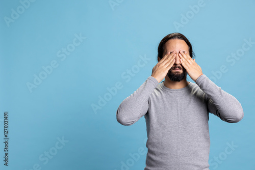 Photography Young adult showing the three wise monkeys symbol with hands over his eyes, covering eye sight to see no evil metaphor