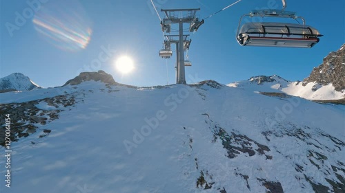 Riding chairlift in winter ski resort of Kaprun in Austrian Alps. Revealing beautiful views of snowy slopes of alpine mountains in sunny day