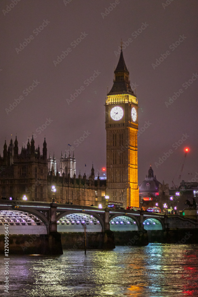 Fototapeta premium A stunning view of Big Ben and Westminster Bridge illuminated against the night sky, with reflections shimmering on the Thames River. The iconic London landmark showcases