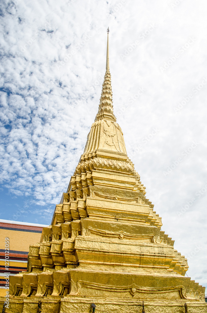 Fototapeta premium Golden stupa against a cloudy sky in Wat Phra Kaew Bangkok Thailand
