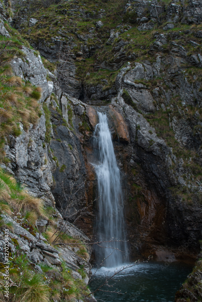 Cascading waterfall amidst rocky terrain creating a serene and untouched natural water feature Cascading waterfall amidst rocky terrain creating a serene and untouched natural water feature