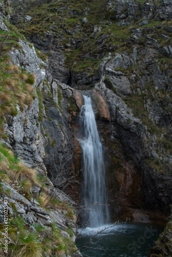 Cascading waterfall amidst rocky terrain creating a serene and untouched natural water feature