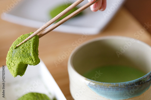 Cup of fresh matcha tea and Warabi mochi, traditional Japanese sweet from bracken starch on wooden table.