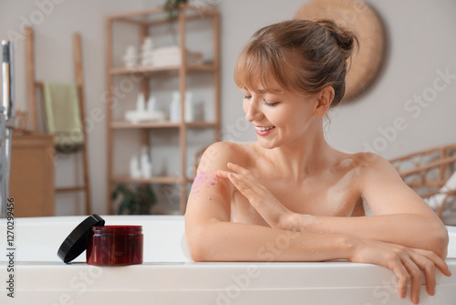 Young woman applying scrub ...