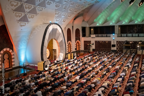 A group of Muslims prostrating in prayer, demonstrating devotion in a grand architectural space. The diverse congregation reflects spiritual unity, faith, and community involvement in a sacred setting photo