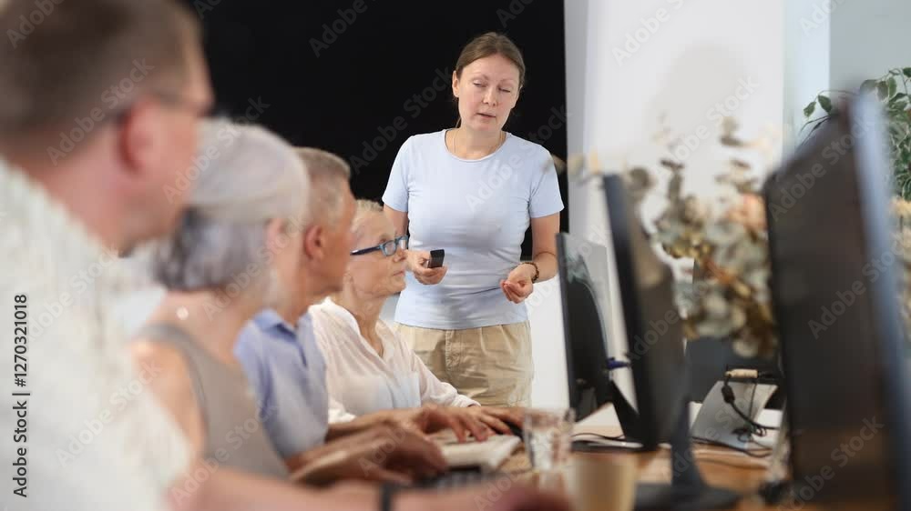 Adult woman teacher teaches group of elderly people to use computer at master class Adult woman teacher teaches group of elderly people to use computer at master class