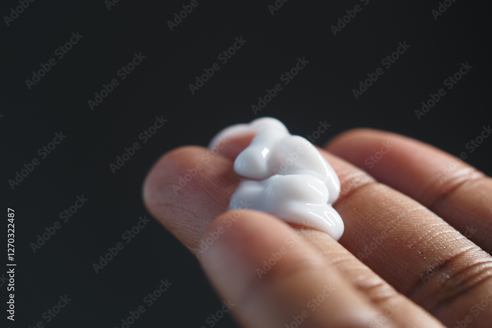 Cream being applied on a person's hand in soft lighting Cream being applied on a person's hand in soft lighting