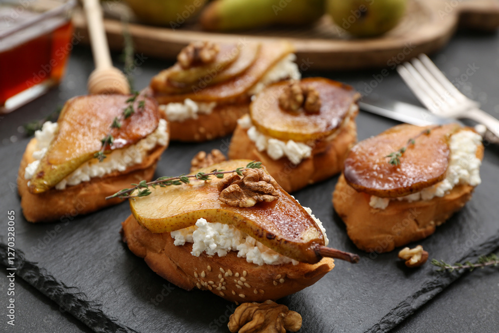 Board of pear bruschetta with ricotta cheese, walnuts and thyme on black background Board of pear bruschetta with ricotta cheese, walnuts and thyme on black background