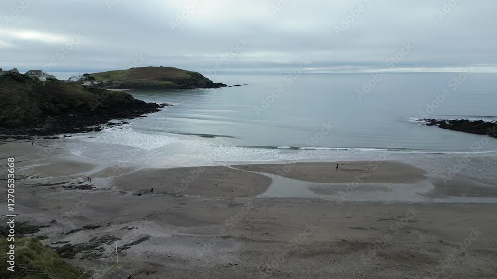 Drone shot of amazing view where sea meets sandy beach in Salcombe, showing gentle waves washing ashore with beautiful coastline and green hills in the background. Drone shot of amazing view where sea meets sandy beach in Salcombe, showing gentle waves washing ashore with beautiful coastline and green hills in the background.