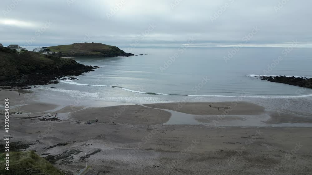 Drone shot of amazing view where sea meets sandy beach in Salcombe, showing gentle waves washing ashore with beautiful coastline and green hills in the background. Drone shot of amazing view where sea meets sandy beach in Salcombe, showing gentle waves washing ashore with beautiful coastline and green hills in the background.