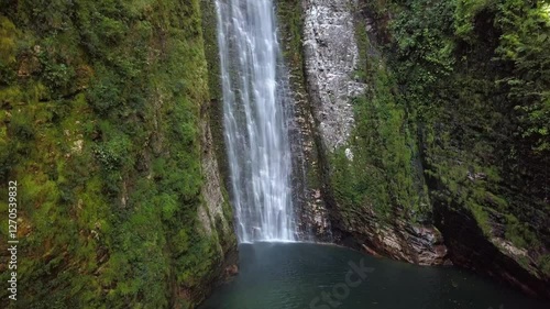 Aerial drone shot rising up, showcasing the powerful fall of the Segredo waterfall amidst the pristine landscape of Chapada dos Veadeiros, Brazil photo