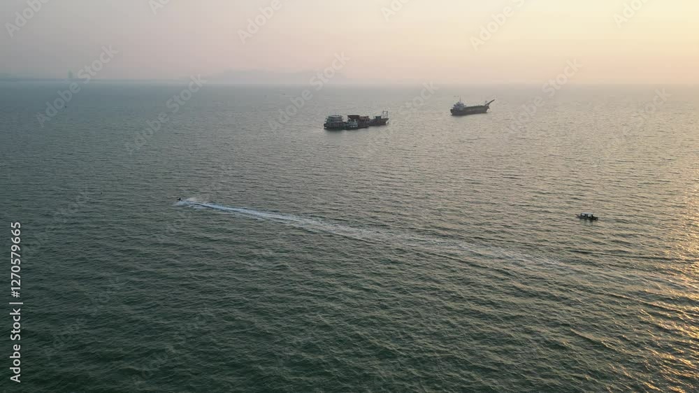 Two ships in distance sailing at sunset with a speedboat and a normal one passed in front of them Two ships in distance sailing at sunset with a speedboat and a normal one passed in front of them