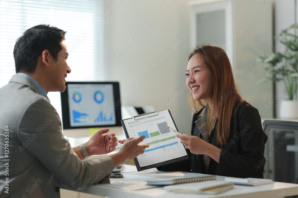 Two asian businesspeople smiling and discussing about financial chart during a meeting in a modern office, analyzing and reviewing company performance, business strategy and planning Two asian businesspeople smiling and discussing about financial chart during a meeting in a modern office, analyzing and reviewing company performance, business strategy and planning