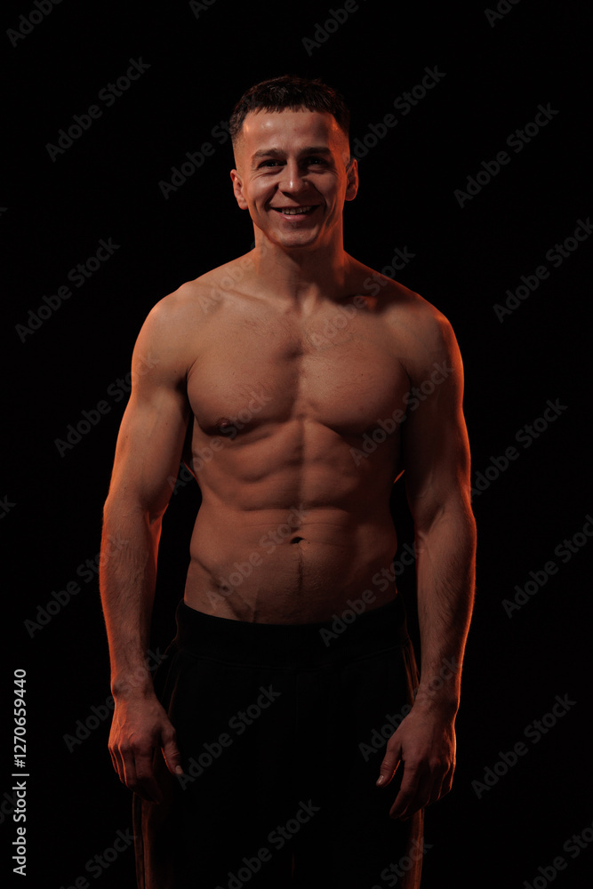 Fototapeta premium Adult male athlete bodybuilder posing on a orange light