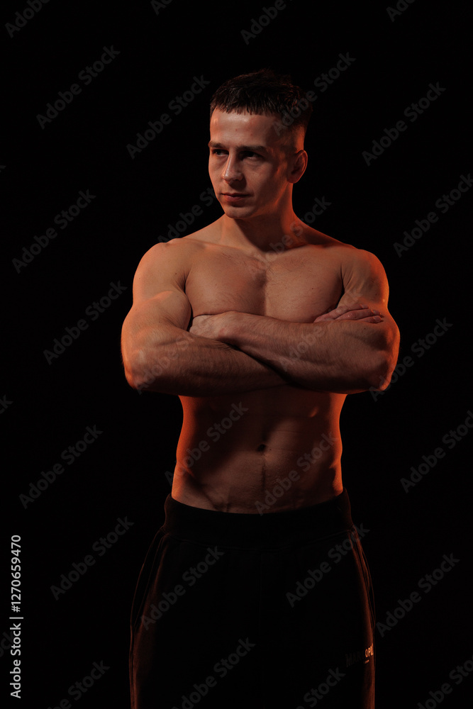 Fototapeta premium Adult male athlete bodybuilder posing on a orange light