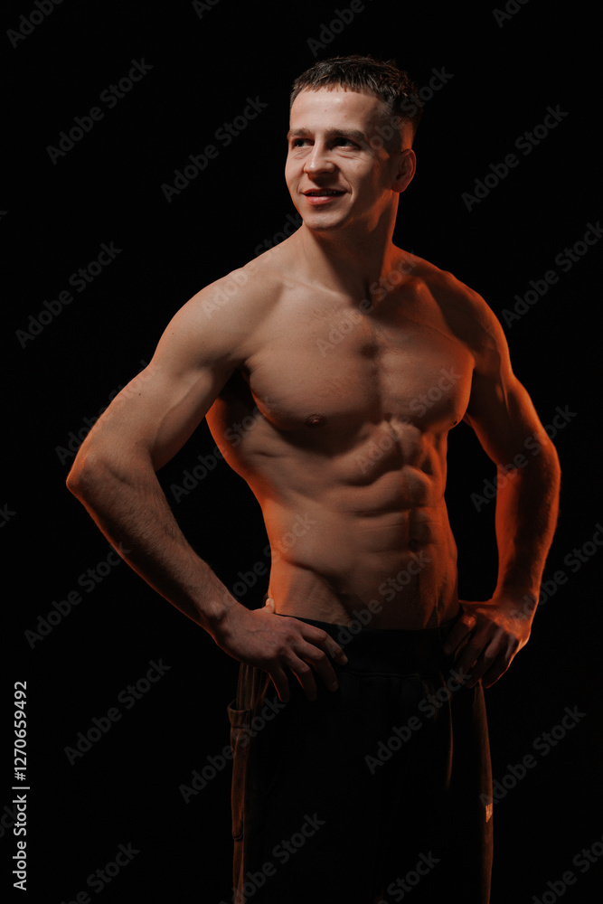 Fototapeta premium Adult male athlete bodybuilder posing on a orange light
