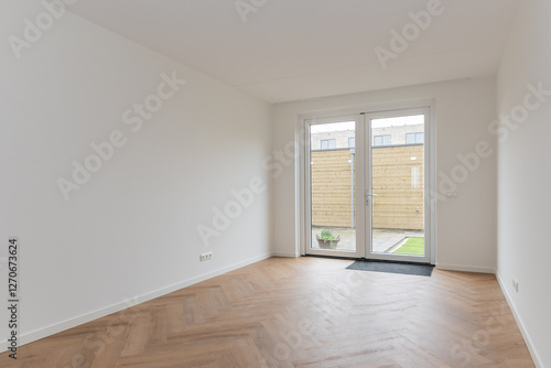 interior living room of modern new build residential smart house looking through glass patio door window at basic back garden plot with wooden shed. Brand new property freshly handed over to new owner