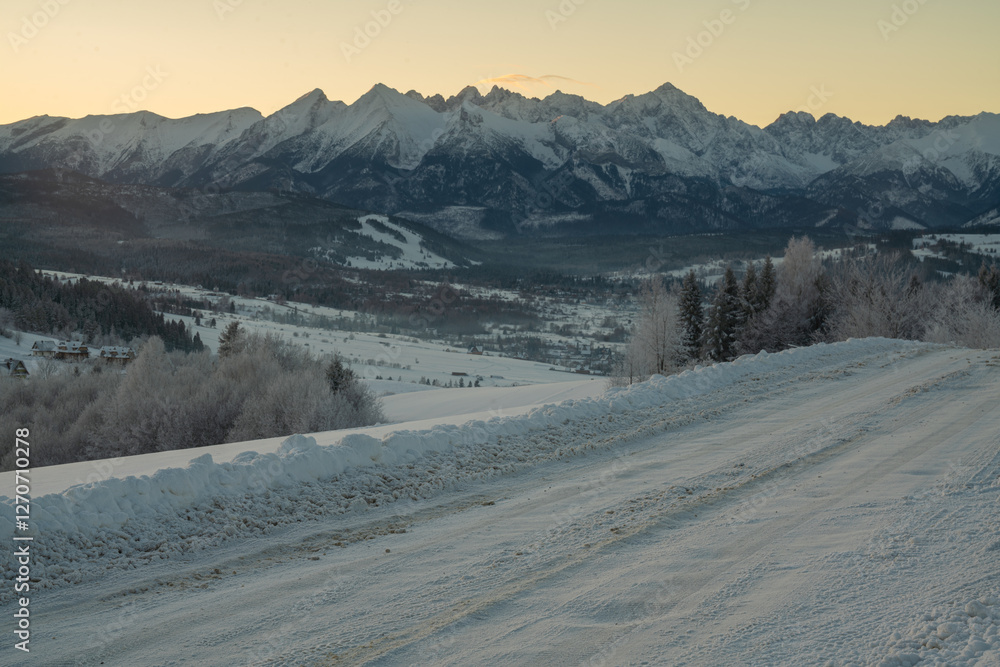 A snow-covered parking lot at a ski resort in the mountains on a frosty morning