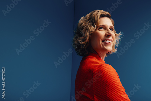Confident middle-aged businesswoman in a vibrant monochromatic set with blue and orange colorblocking, looking determined