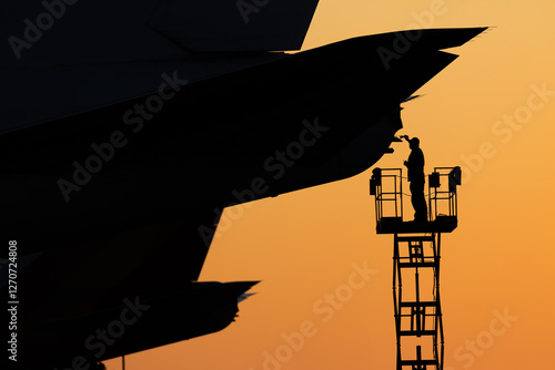 Aircraft mechanic repairing aircraft at sunset photo