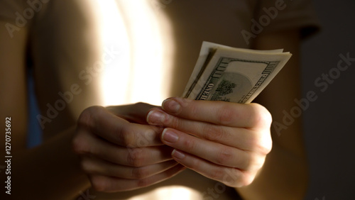 A person carefully counts several bills in soft, natural light. The focus is on the hands and cash, creating a serene atmosphere of financial management at home.