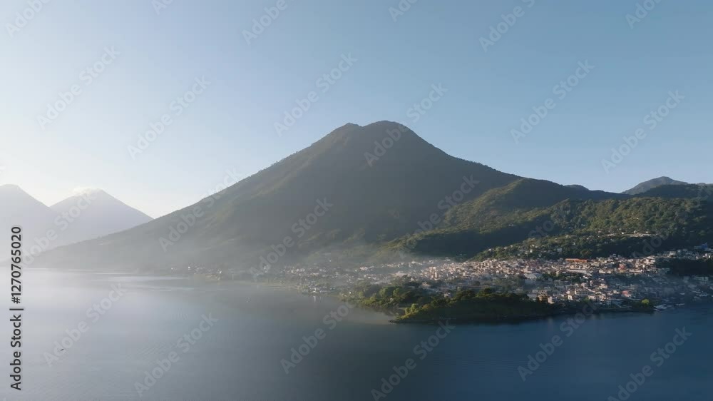 Slow panning drone shot of San Pedro La Laguna village at sunrise, as mist drapes over Lake Atitlan, Guatemala creating a dreamlike atmosphere.