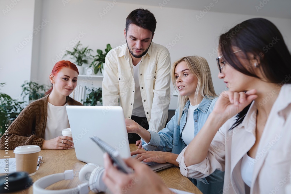 Blond businesswoman explaining ideas through laptop to colleague in office Blond businesswoman explaining ideas through laptop to colleague in office