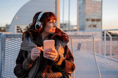 Contemplative woman listening to music through wireless headphones photo