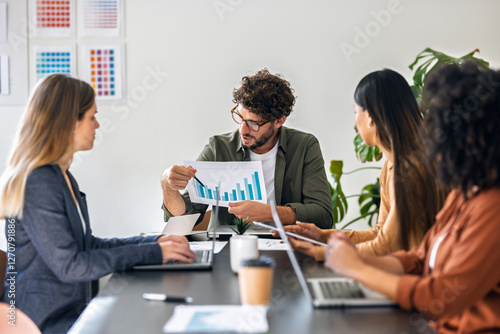 Businessman explaining bar graph to colleagues in meeting at office photo