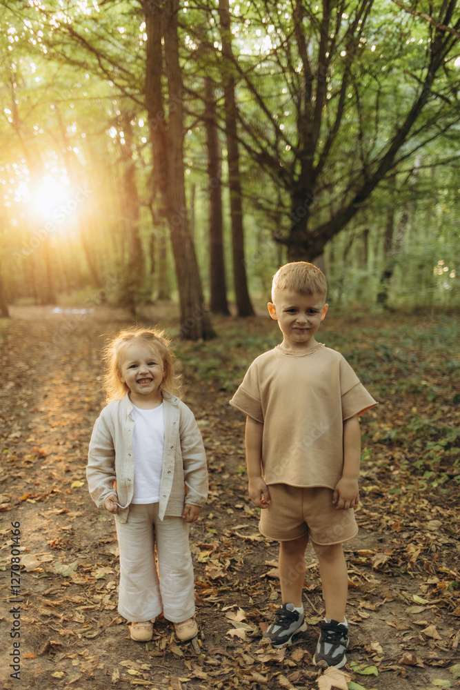 Smiling Siblings Standing Together in a Sunlit Forest Path in Autumn Smiling Siblings Standing Together in a Sunlit Forest Path in Autumn