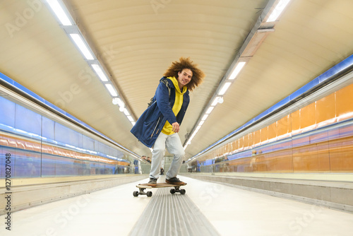 Young man skateboarding in subway corridor with moving walkway photo