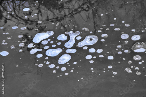 Bąble powietrza uwięzione pod lodem tworzą nieregularne jasne plamy photo