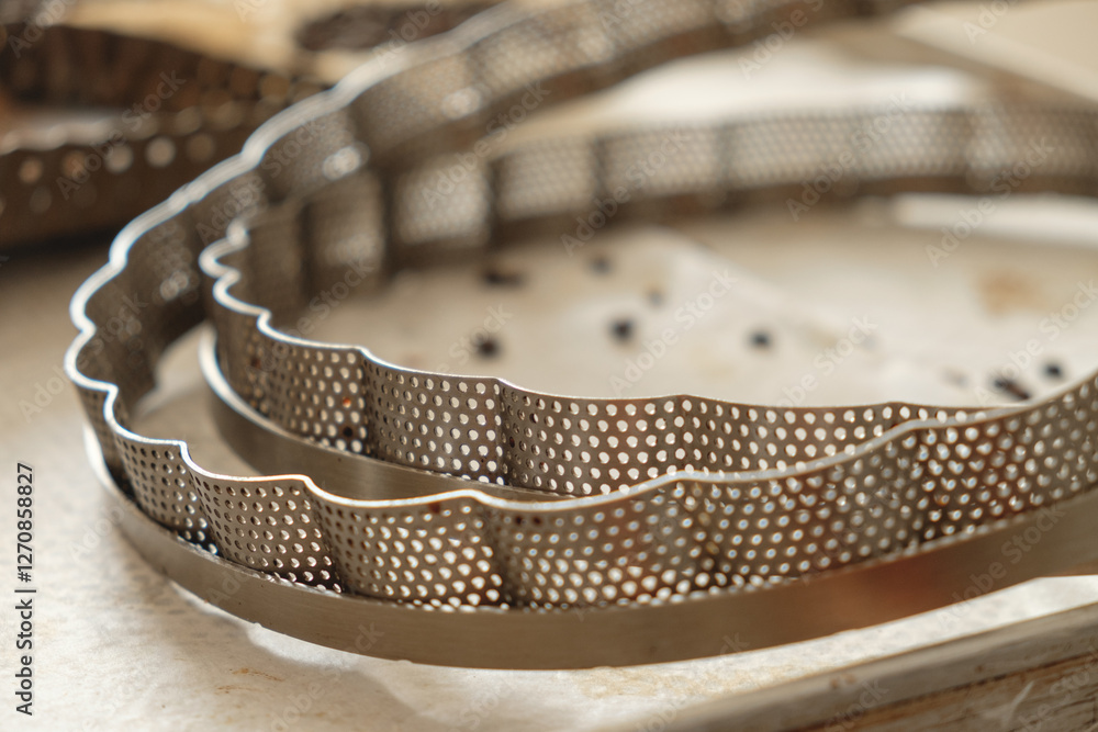 Metal baking molds arranged neatly on a kitchen countertop, showcasing intricate perforations and elegant designs, perfect for creating delicious baked goods Metal baking molds arranged neatly on a kitchen countertop, showcasing intricate perforations and elegant designs, perfect for creating delicious baked goods