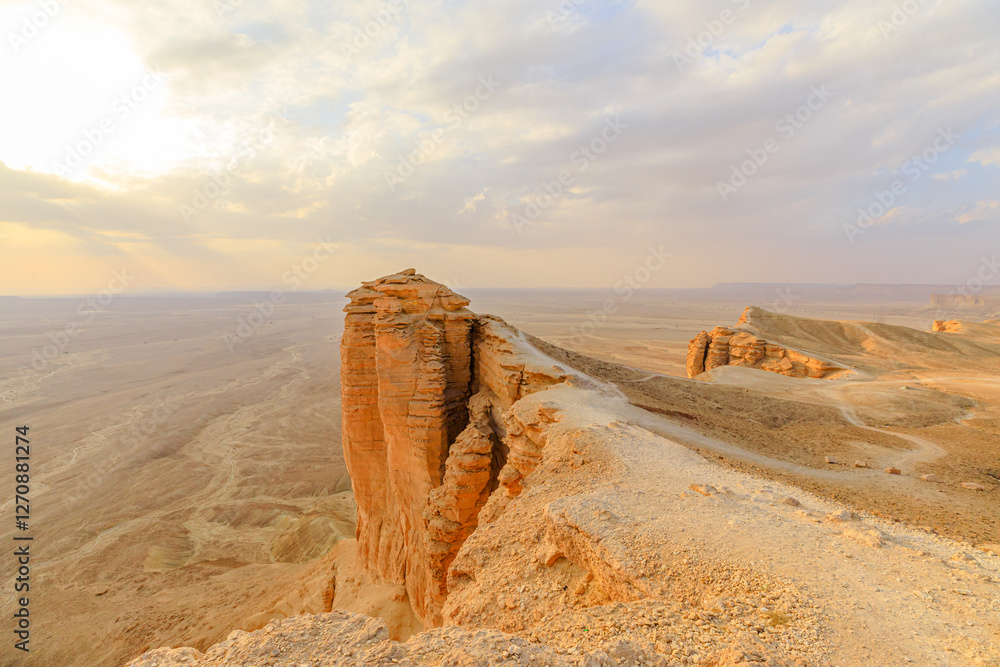 Golden hour sunlight illuminates the Tuwaiq escarpment at sunset, casting long shadows across the desert landscape near Riyadh, Saudi Arabia, a breathtaking view from the edge of the world