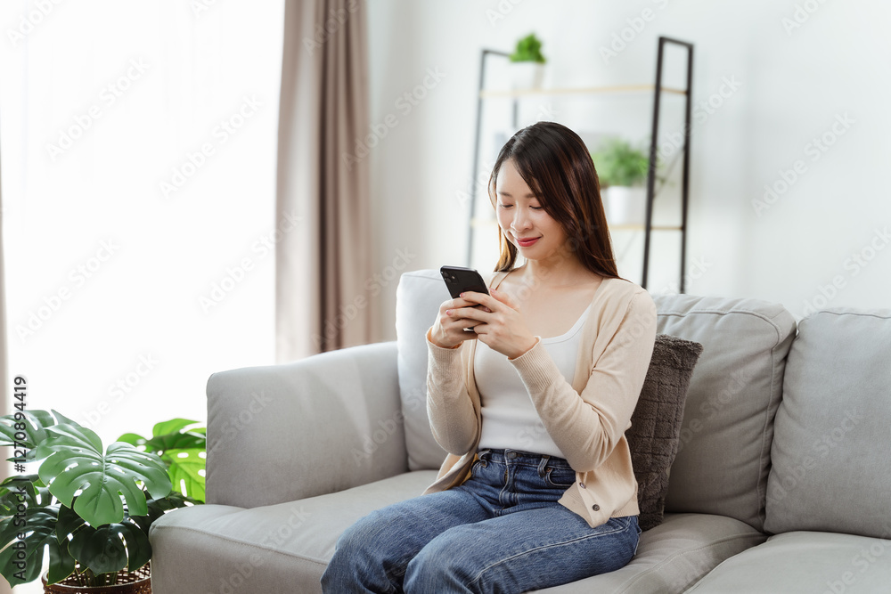 Obraz premium Beautiful young woman holding and using a smartphone, using social media, shopping online