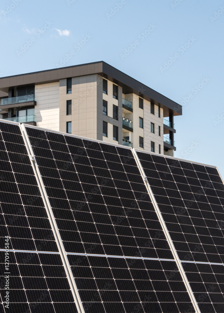 Fototapeta premium Large solar panel with residential city house in the background. Sustainable energy concept. 