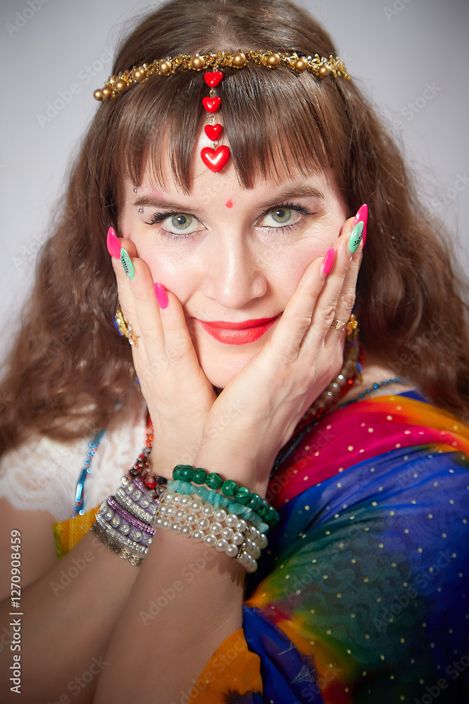 Naklejka premium Blonde woman models vibrant sari while showcasing traditional Indian jewelry in a studio setting