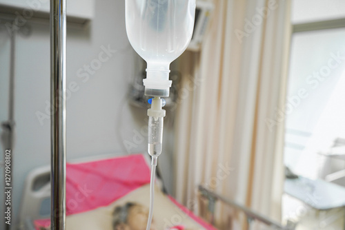 Photos Close-up of intravenous saline  infusion set for patient with blurred patient background in hospital