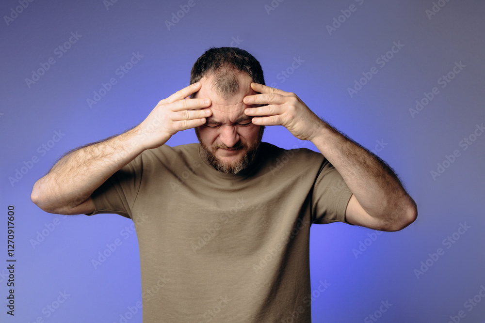 A man has a severe headache. He holds his head in his hands and massages his temples to relieve the pain in his head. Changes in atmospheric pressure affect physical condition and headaches. A man has a severe headache. He holds his head in his hands and massages his temples to relieve the pain in his head. Changes in atmospheric pressure affect physical condition and headaches.