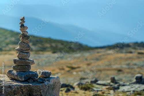 A tall balanced stone cairn stands in sharp focus against a blurred mountain plateau landscape in Serra da Estrela Portugal