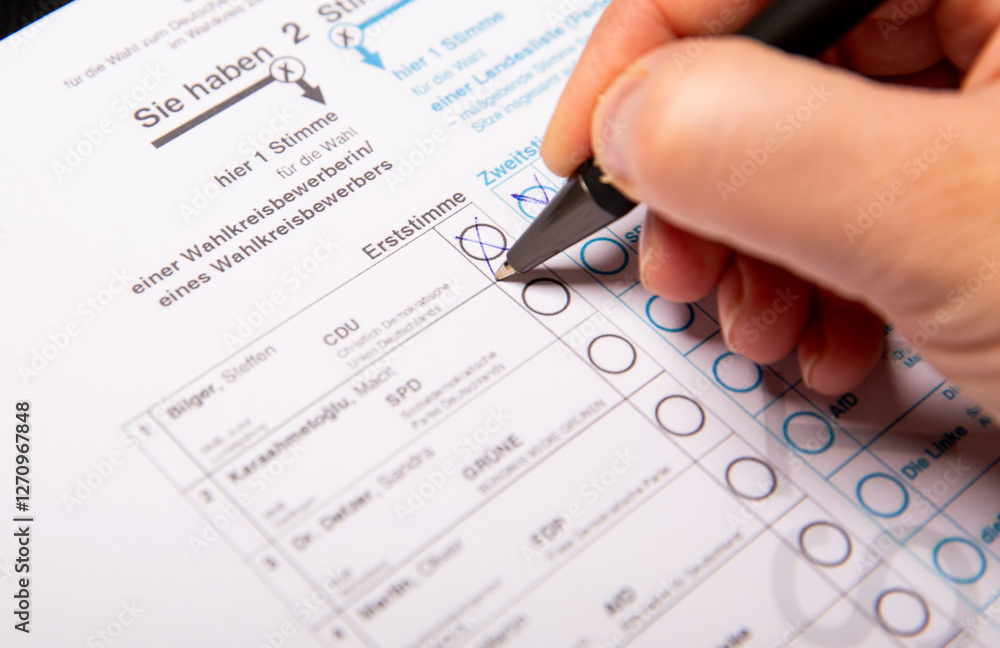 12. February 2025 - Berlin, Germany. Close up of a female hand marking CDU party on a ballot paper with a pen 12. February 2025 - Berlin, Germany. Close up of a female hand marking CDU party on a ballot paper with a pen