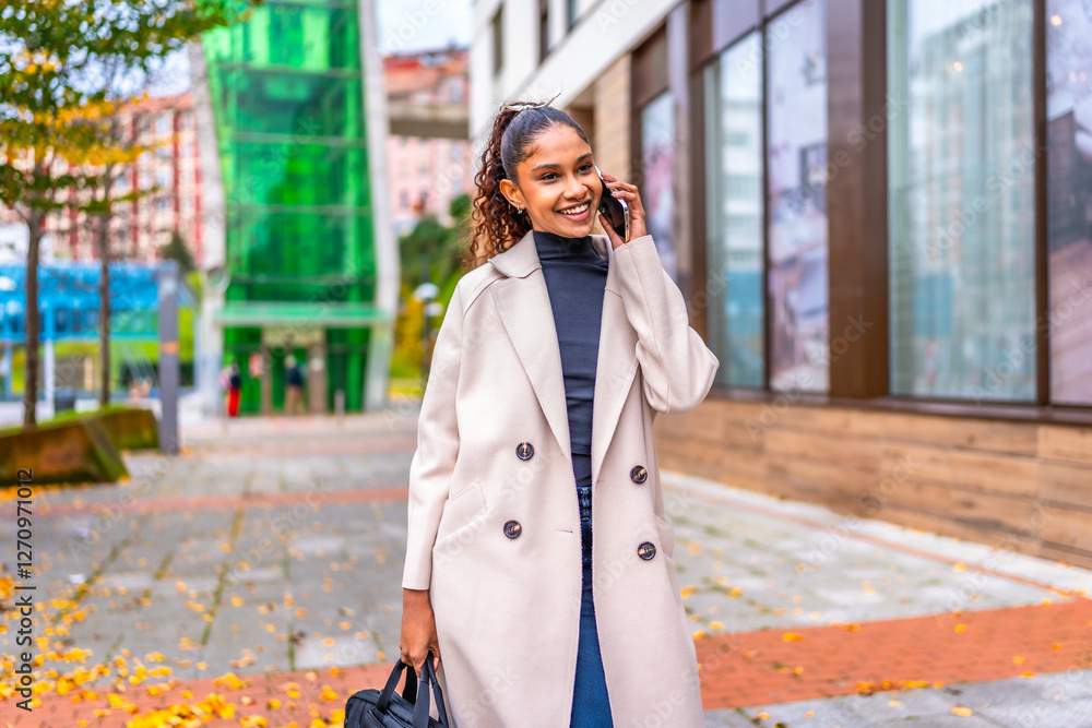 Fototapeta premium African businesswoman walking while talking to the mobile phone outdoors