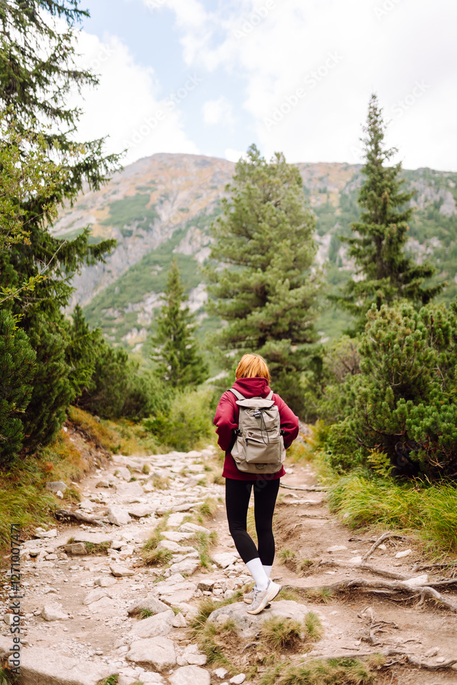 Naklejka premium Woman traveler walking on mountains cliff in summer sunny day under sun light. Adventure active. Tourism