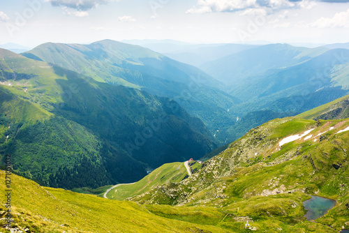 Obraz na płótnie mountain landscape of romania in summer. vacation season. beautiful outdoor scenery with alpine lake. scenic view in to the valley. travel background with blue sky and clouds. grassy slope w salonie