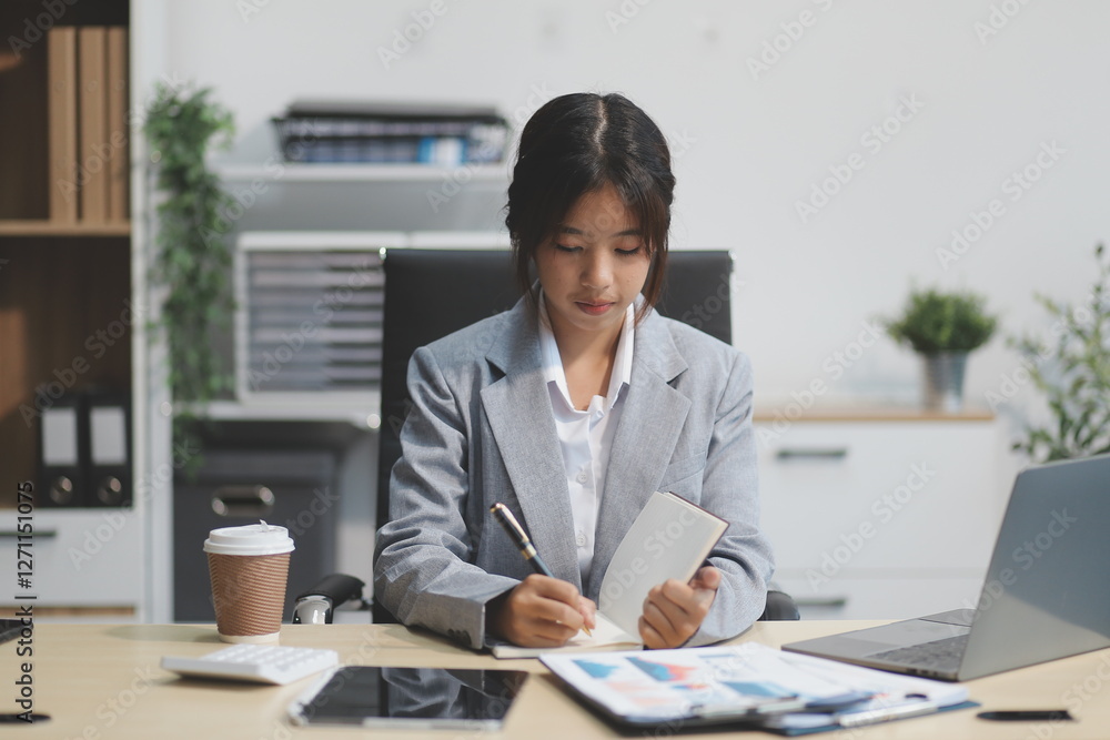 Successful Asian businesswoman smiling using laptop computer and holding coffee cup at office. Confident Asia businesswoman sitting happily in the office. Successful Asian businesswoman smiling using laptop computer and holding coffee cup at office. Confident Asia businesswoman sitting happily in the office.